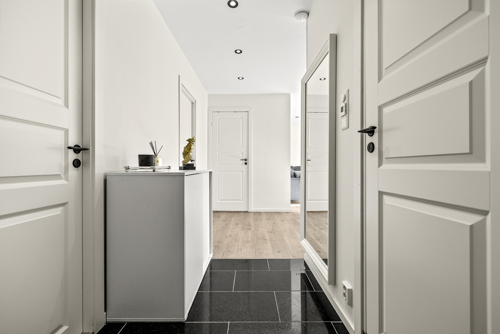 Speil på veggen gir en romslig følelse og reflekterer lys i entréen. Galleribilde