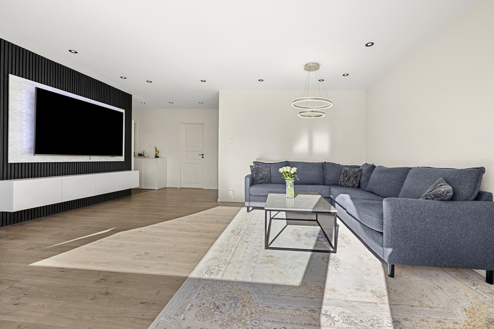 Vegghengt TV og innebygd belysning skaper et moderne preg i oppholdsrommet. Galleribilde