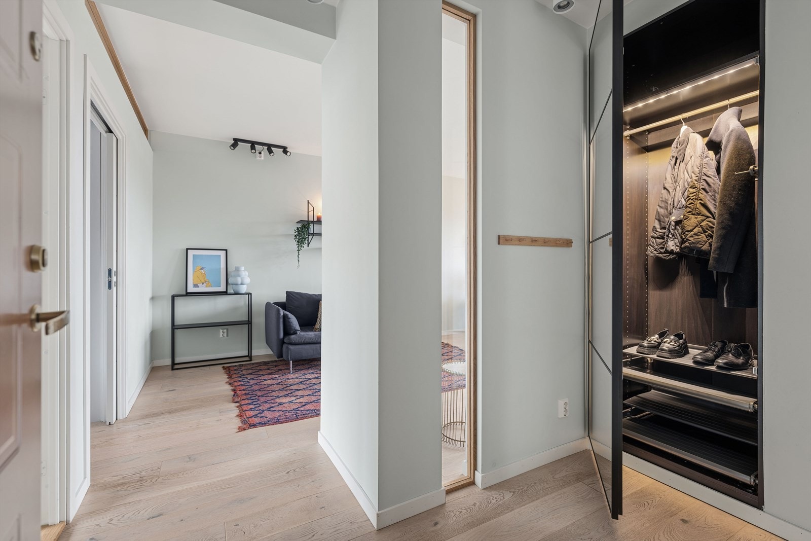 Her er det også direkte inngang til en praktisk garderobenisje. Denne løsningen gjør det enkelt å holde rommet ryddig og gir en sømløs overgang mellom oppbevaring og oppholdsrom. Galleribilde