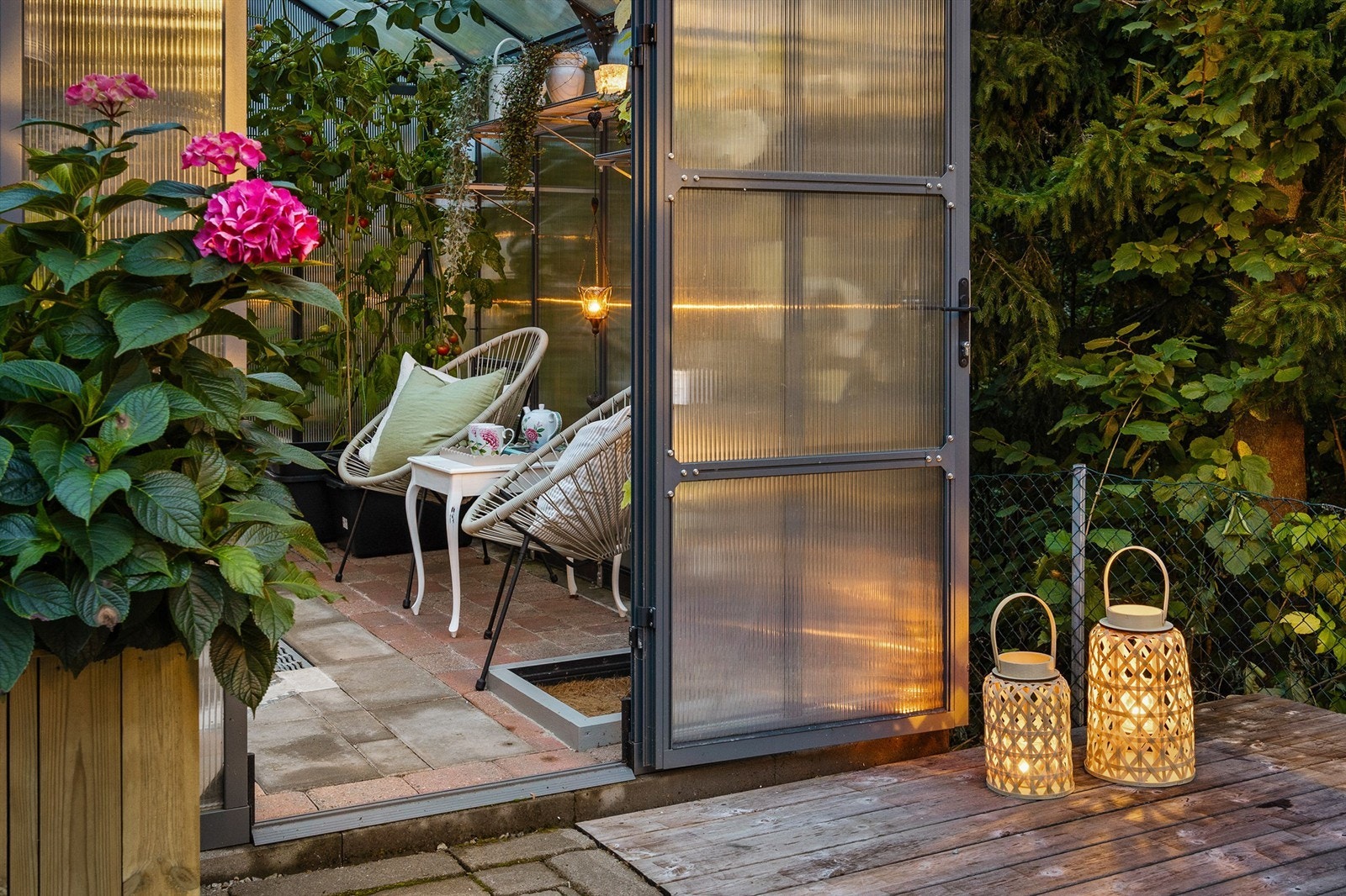 Tilgang til et frittstående drivhus på 9 kvm med belegningsstein på gulv og innlagt strøm/strømuttak, mellom boligen og garasjen. Galleribilde