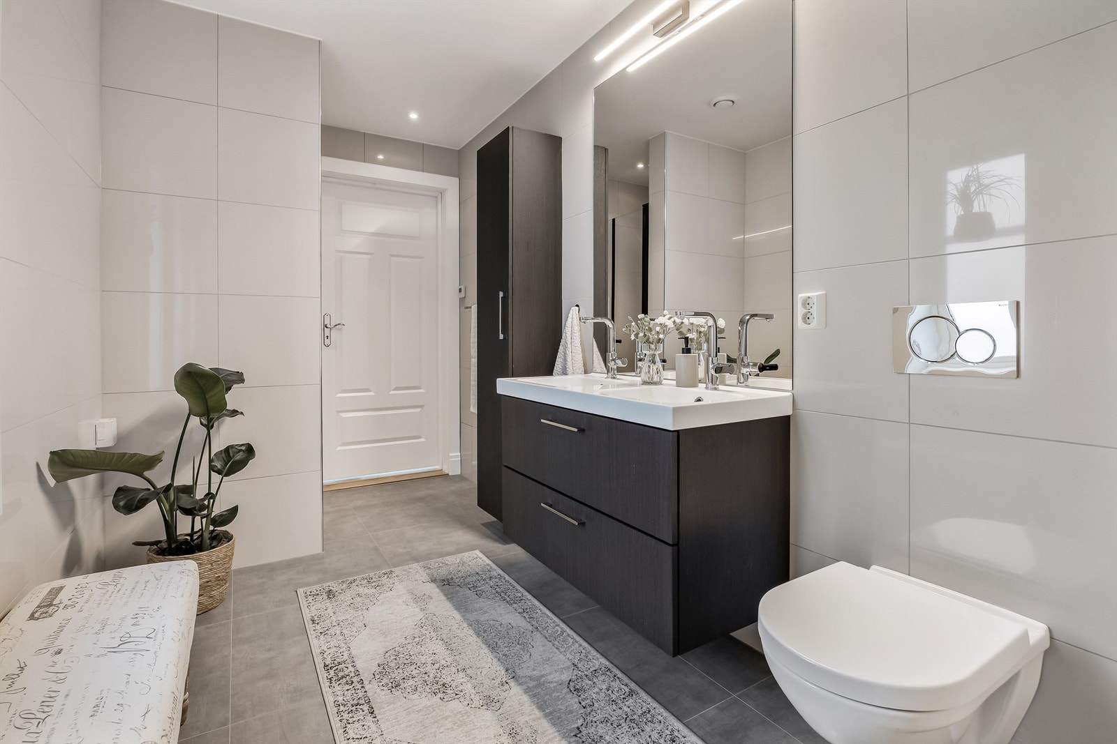 Badet i første etasje er flislagt og har en mørk innredning med dobbel servant. Galleribilde