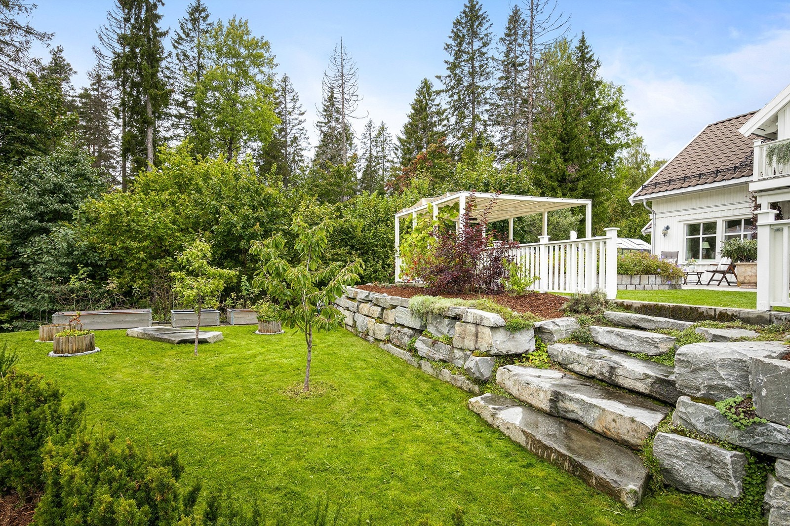 Tomten er opparbeidet i nivåer med solide forstøtningsmurer og trapper i naturstein. Galleribilde