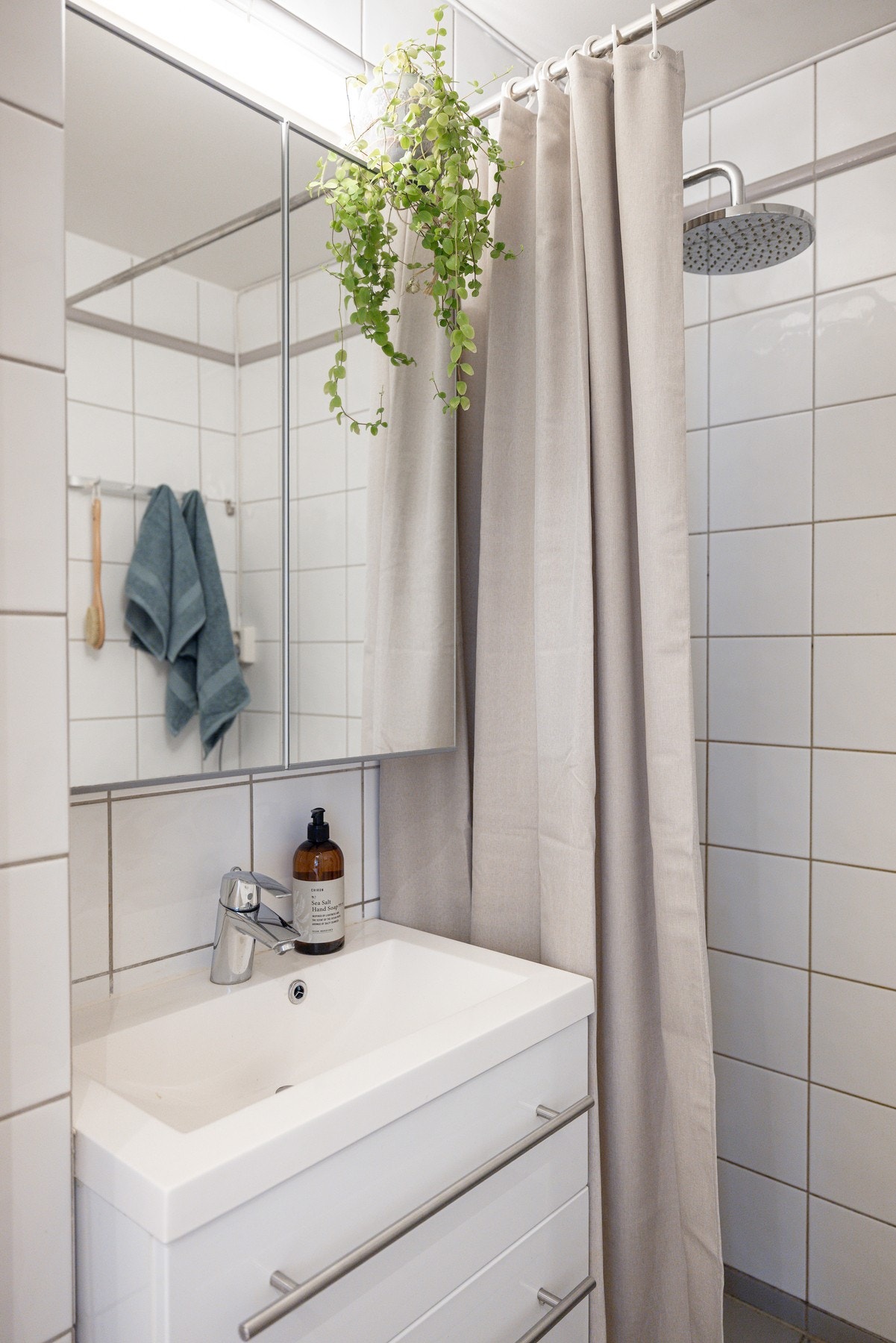 Tidløs baderomsinnredning med lyse fronter, heldekkende servant og speilskap med belysning over. Galleribilde