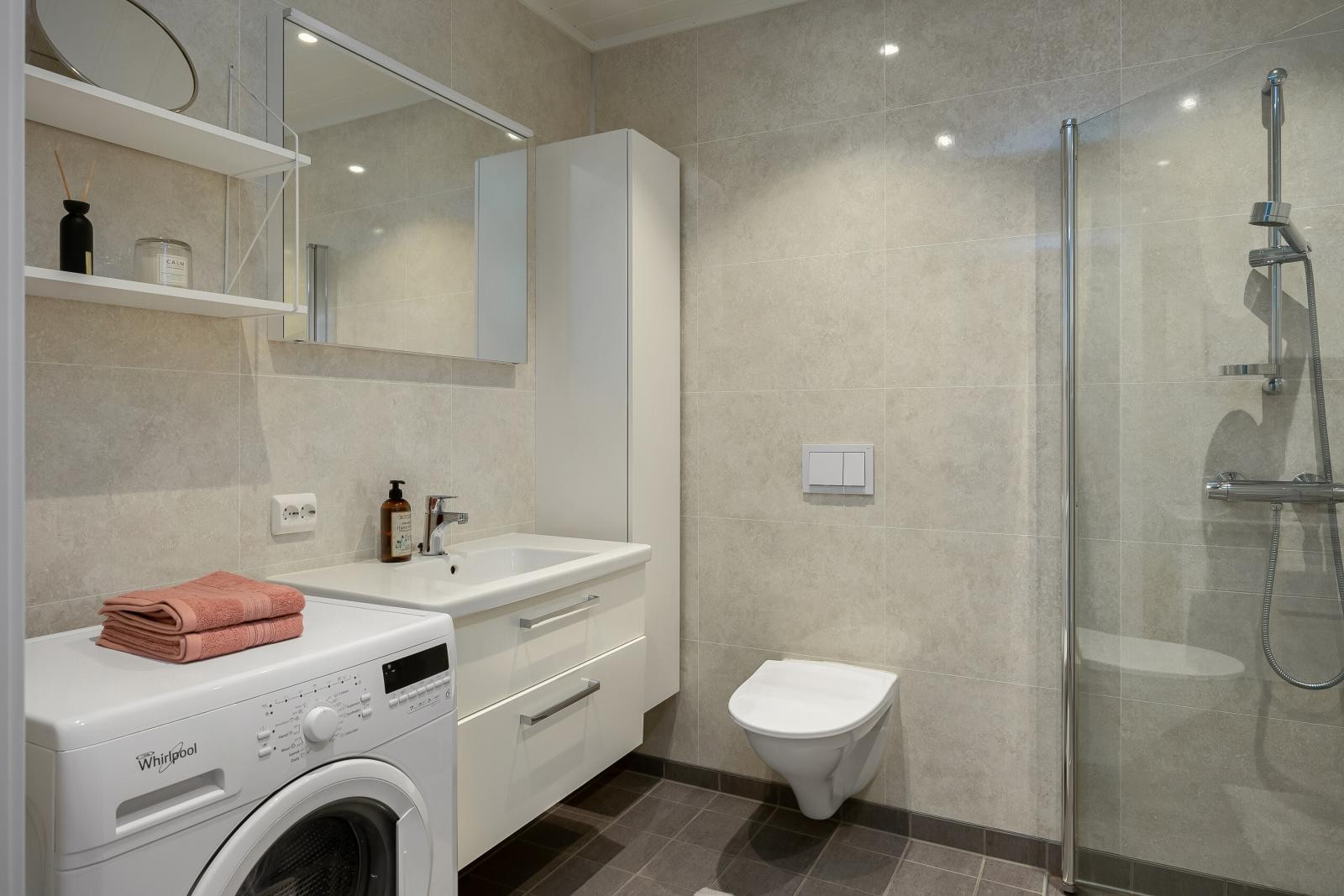 Badet har vegghengt toalett, opplegg for vaskemaskin, dusjhjørne og baderomsinnredning. Galleribilde