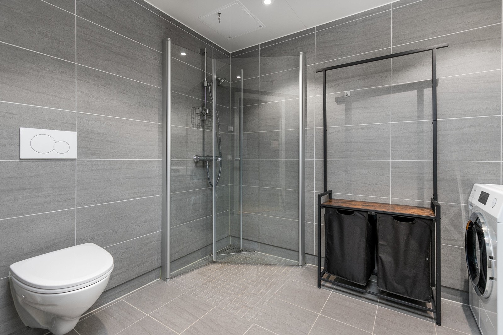 Baderomsinnredning, dusj, veggfestet klosett og opplegg til oppvaskmaskin. Galleribilde