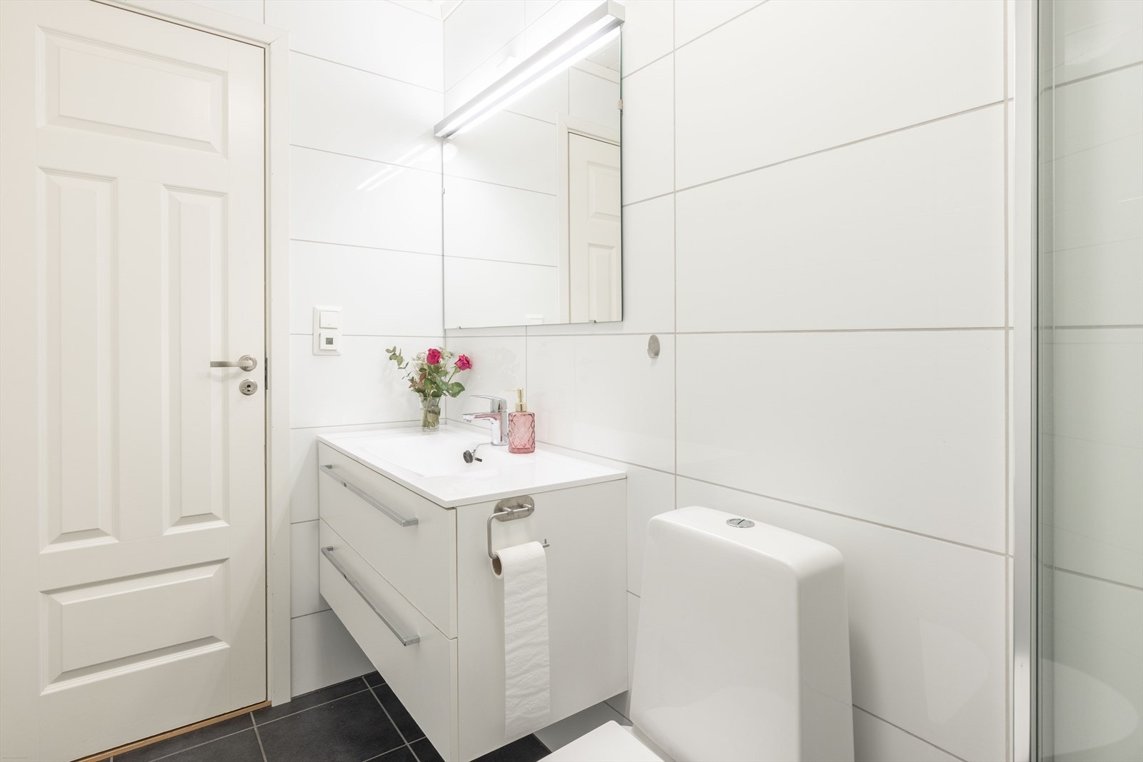 Delikat og helfliset bad med dusjhjørne, servantinnredning og toalett. Galleribilde