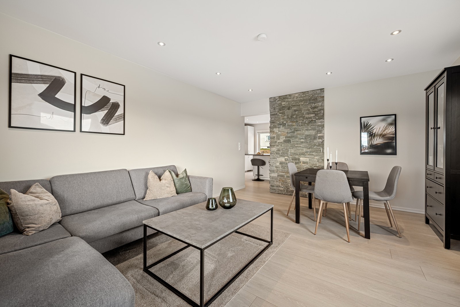 Stuen oppleves som lys og innbydende med 1-stavs laminat på gulv og slette overflater på vegg malt i en dus fargetone. Galleribilde