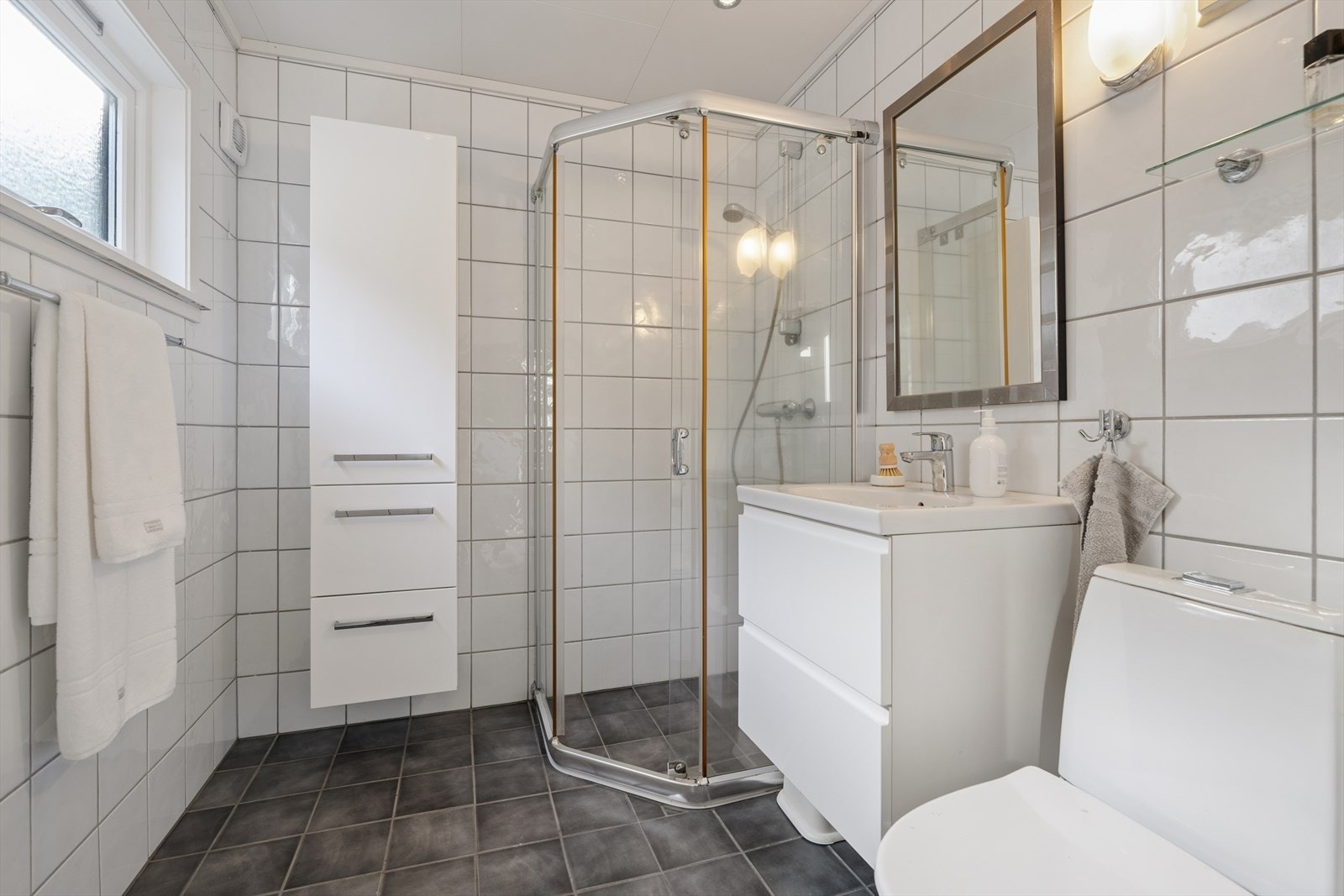 Badet ved entréen er fra 2004, med flislagte overflater, gulvvarme og dusjhjørne. Galleribilde