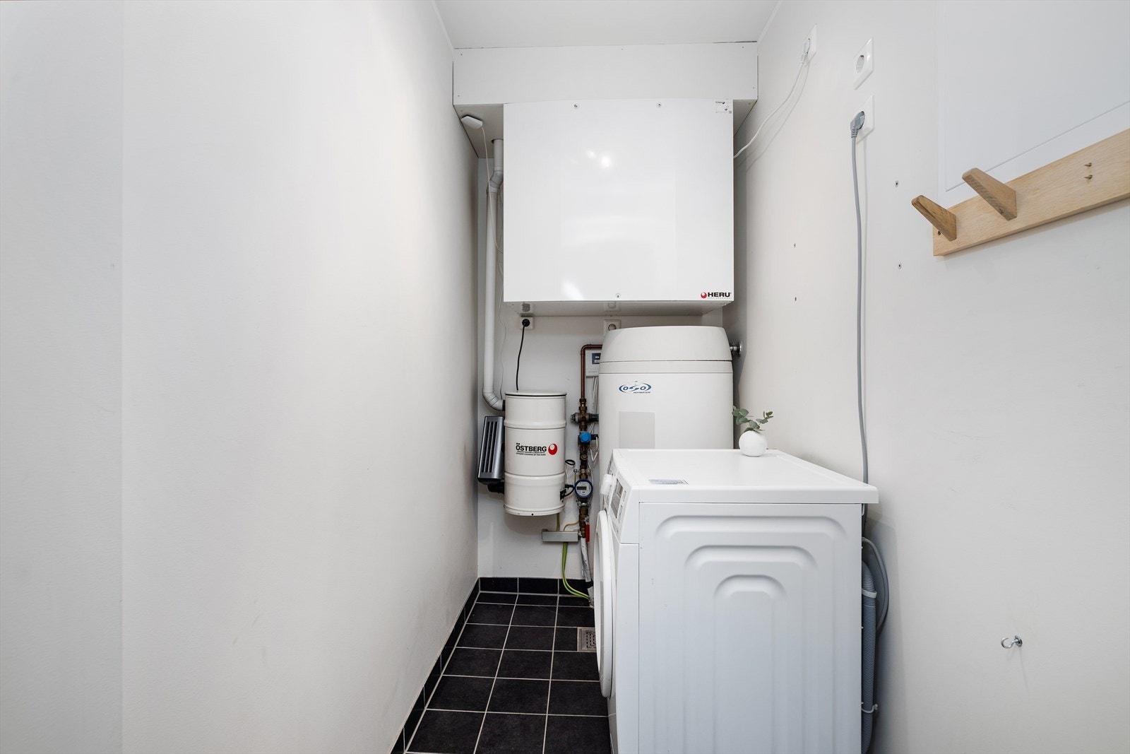 Praktisk vaskerom med flislagt gulv, gulvvarme og opplegg for vaskemaskin. Galleribilde