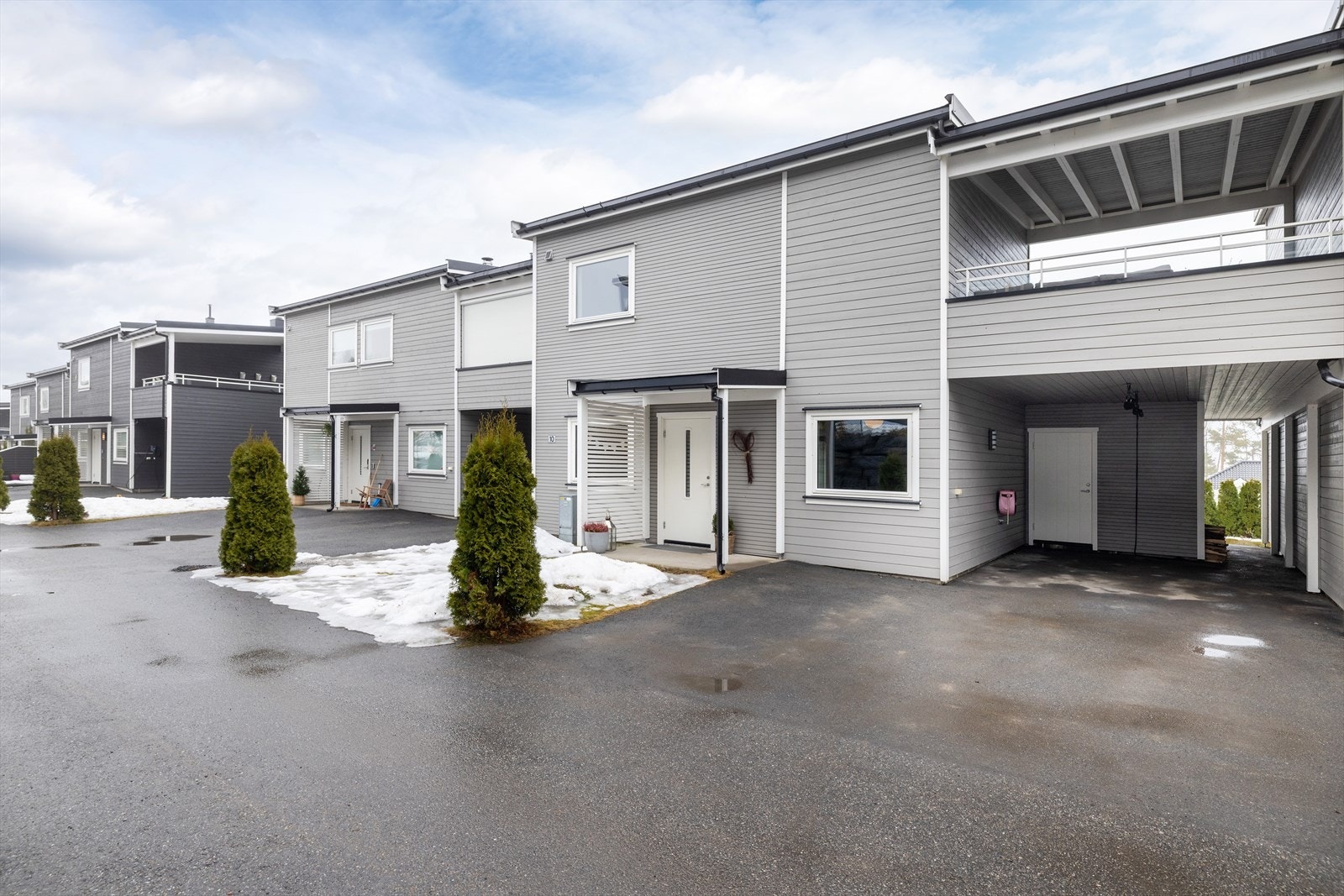 Asfaltert gårdsplass med overbygget inngangsparti og carport med plass til én bil. Galleribilde