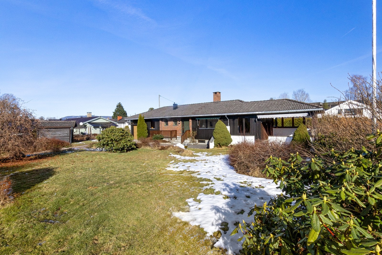 Stor tomt opparbeidet med prydbusker og plen. Galleribilde