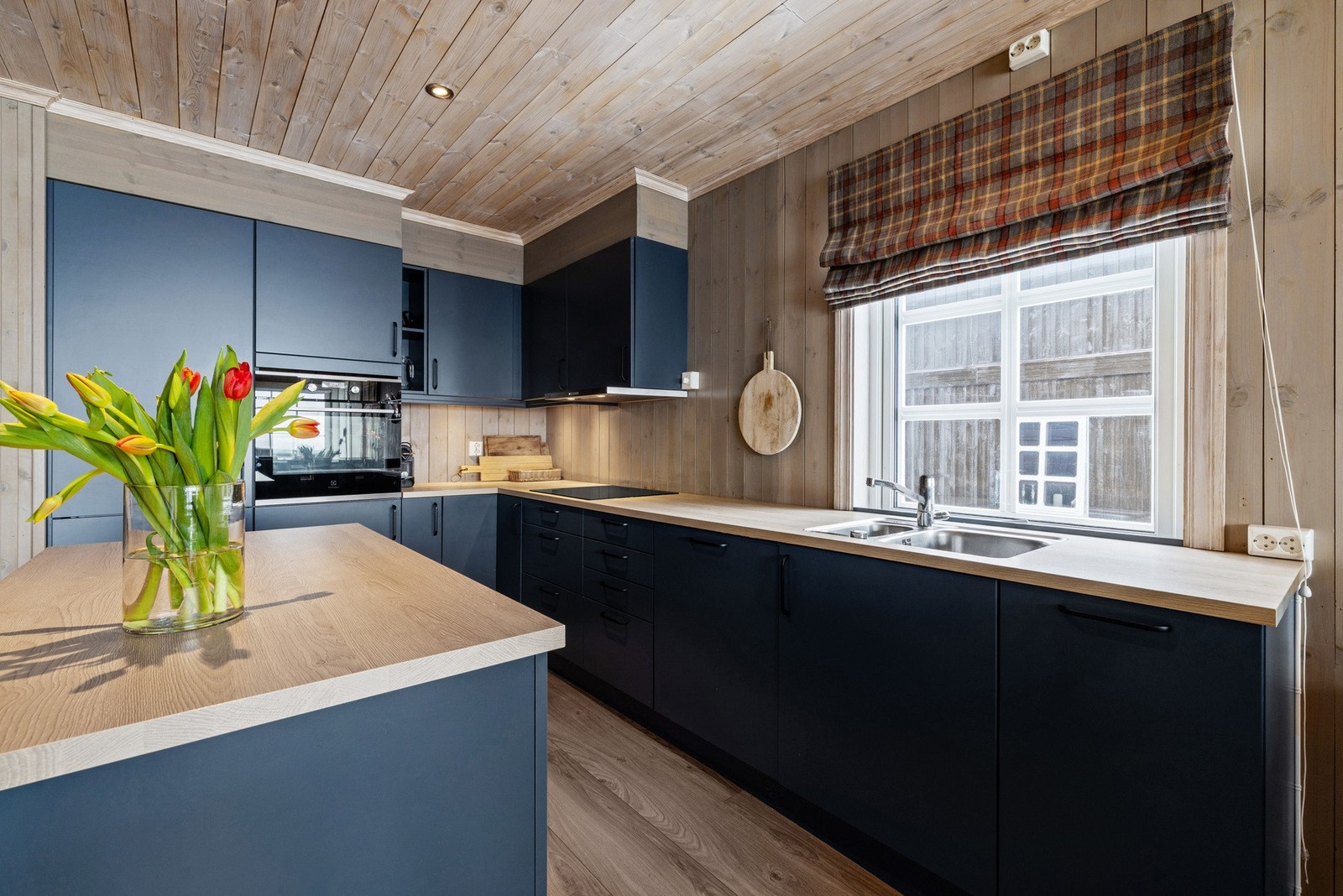 Kjøkkeninnredningen har glatte fronter i en dyp blå tone kombinert med laminat benkeplate. Galleribilde