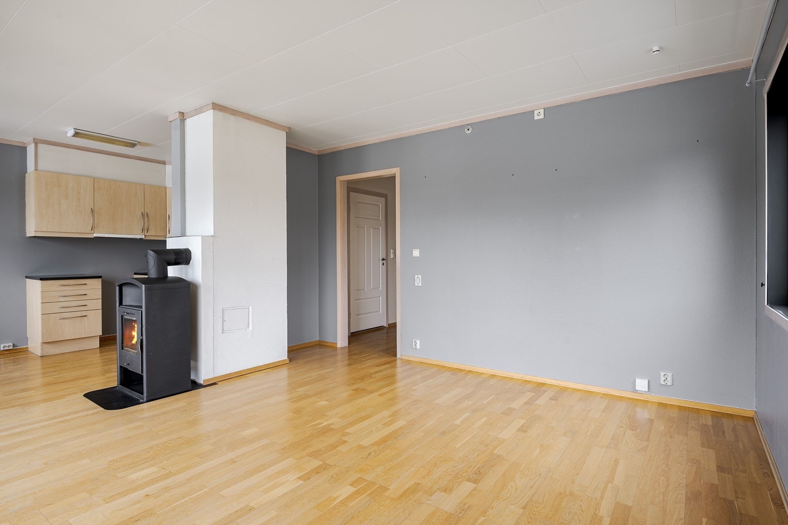 Parkettgulv og malt strietapet i nøytral gråtone på veggene. Galleribilde