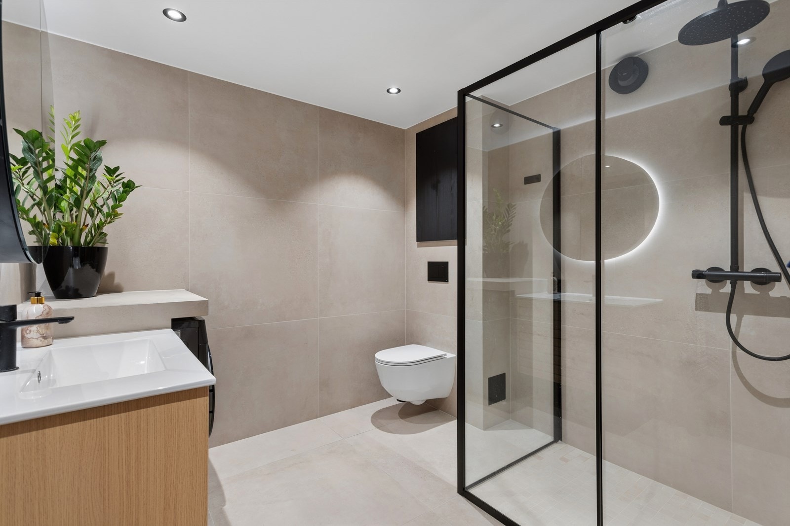 Lekkert bad fra 2024 med ervant med servantskap, veggfestet toalett med skjult sisterne, hjørnedusj med stål og glassdører, nedsenket gulv i dusjen.
Opplegg for vaskemaskin. Galleribilde