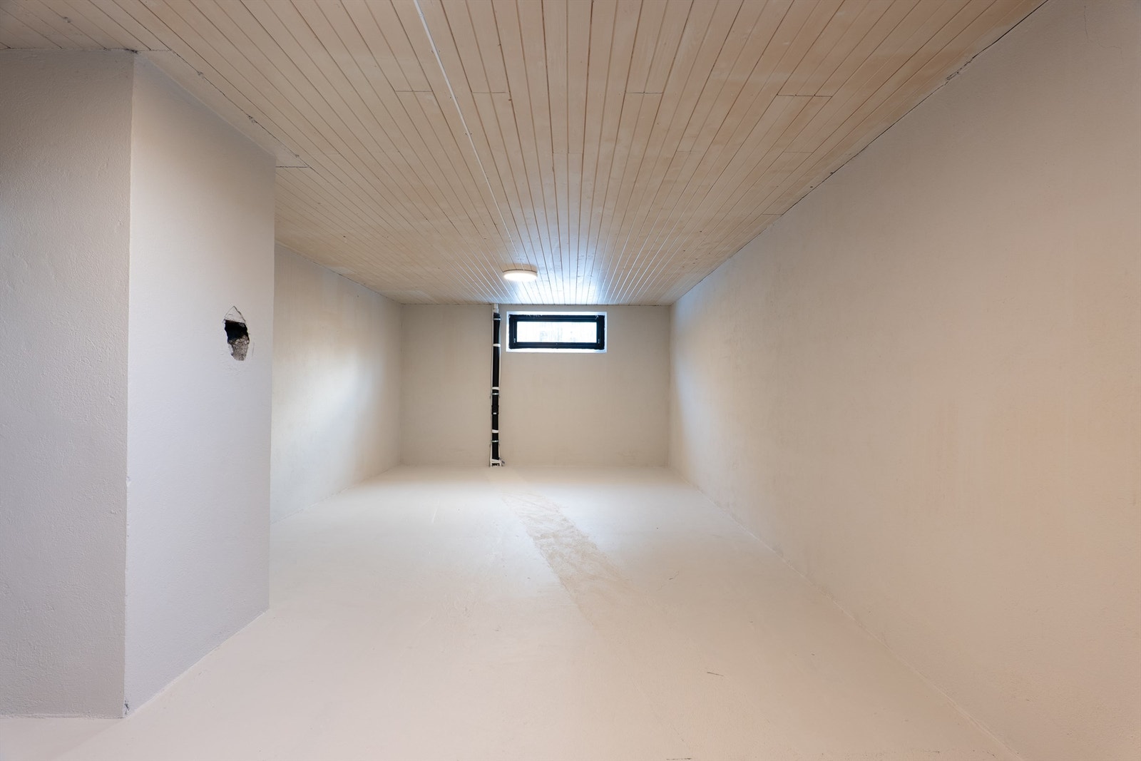 I kjellerens ulike rom og boder er eksisterende overflater malt og nye vinduer installert. Dette store rommet er byggemeldt som hobbyrom. Galleribilde