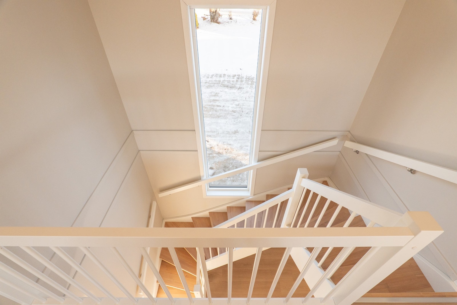Østveggens vertikalstilte vindu fyller trappen med naturlig overlys. Åpne trinn slipper dagslyset helt ned til stuen. Galleribilde
