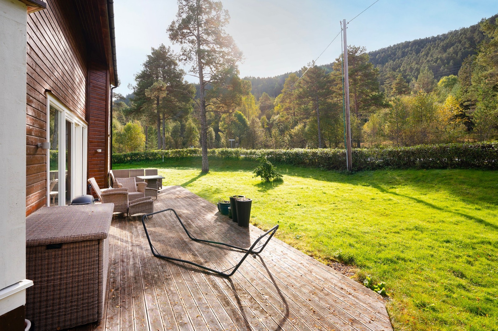 Det er bygget en stor terrasse på bakkeplan i trekonstruksjon med dekke av terrassebord. Galleribilde