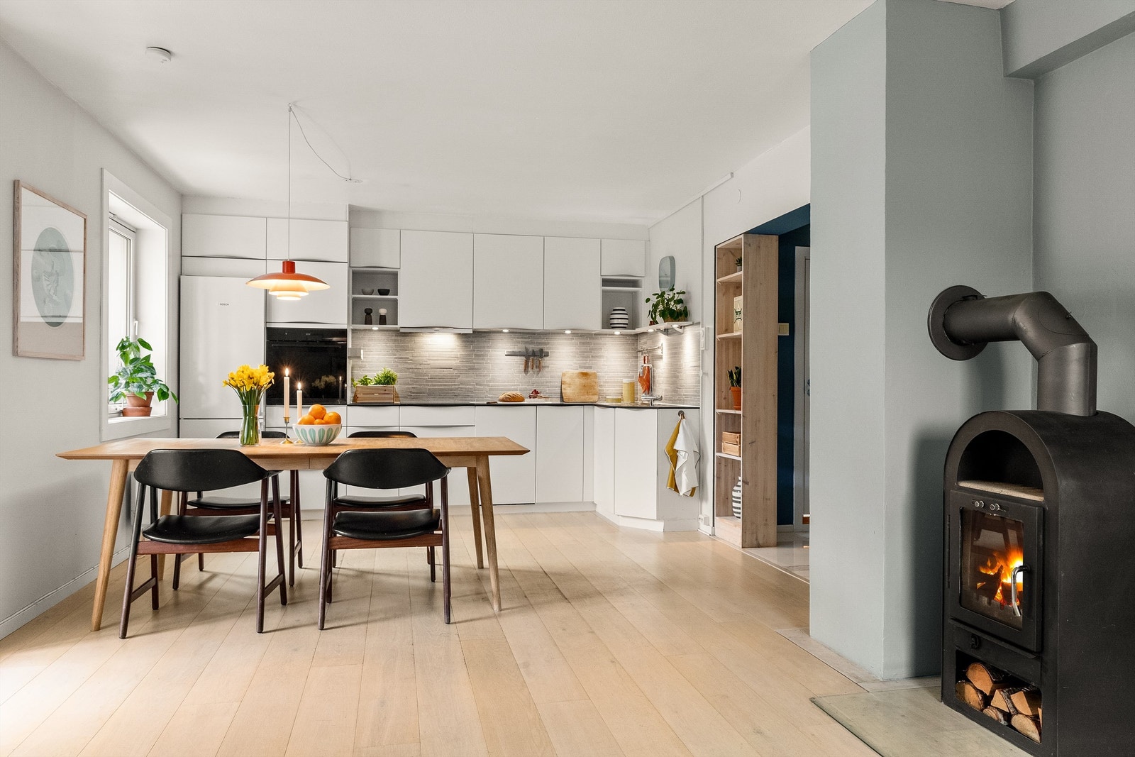 Leiligheten har en åpen og sosial løsning mellom kjøkken og stue, hvor vedovnen skaper ekstra hygge. Foto: Fotostallen v/ Lars-Petter Skillestad Galleribilde