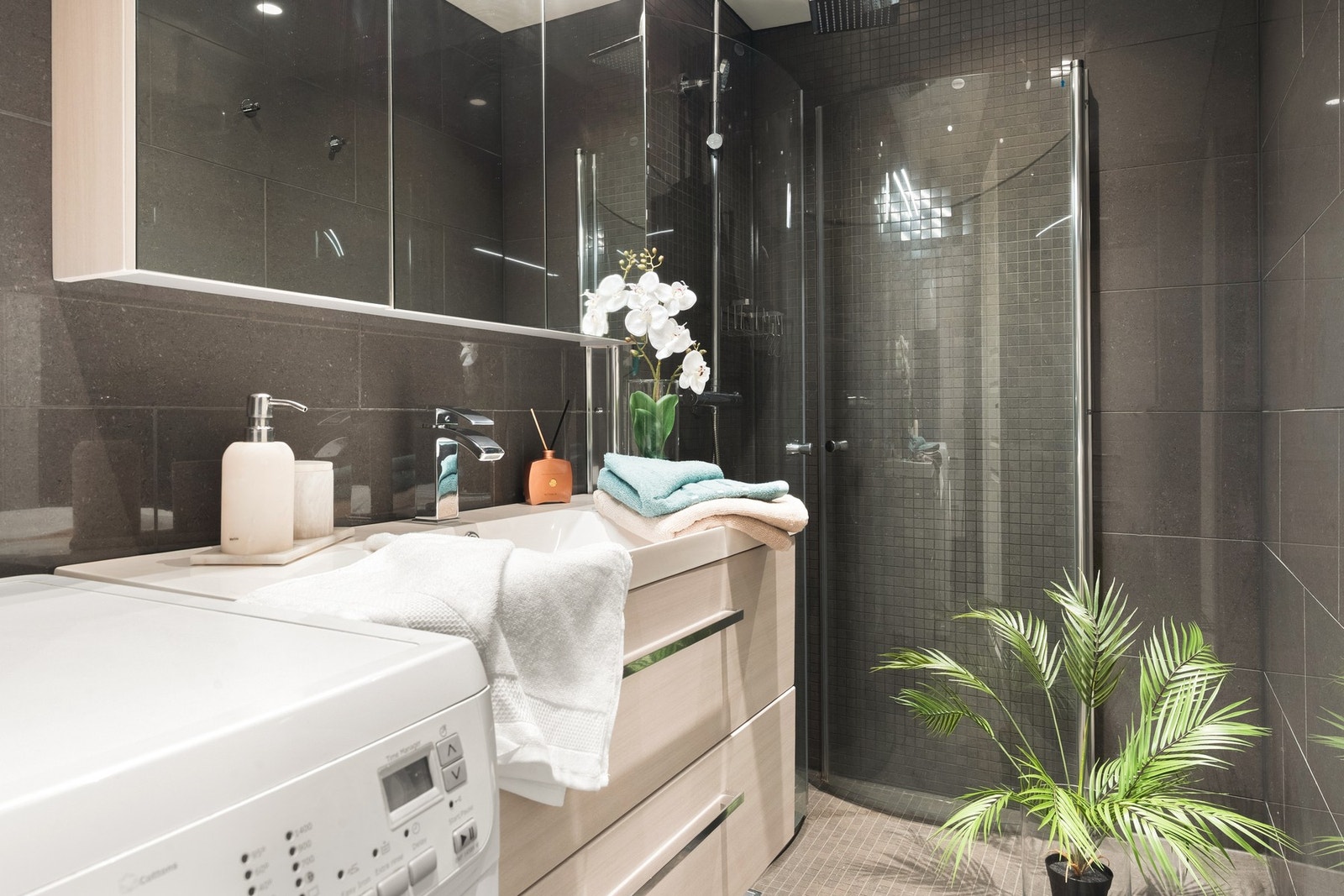 Badet er innredet med servant med innredning, dusjhjørne og opplegg for vaskemaskin. Galleribilde