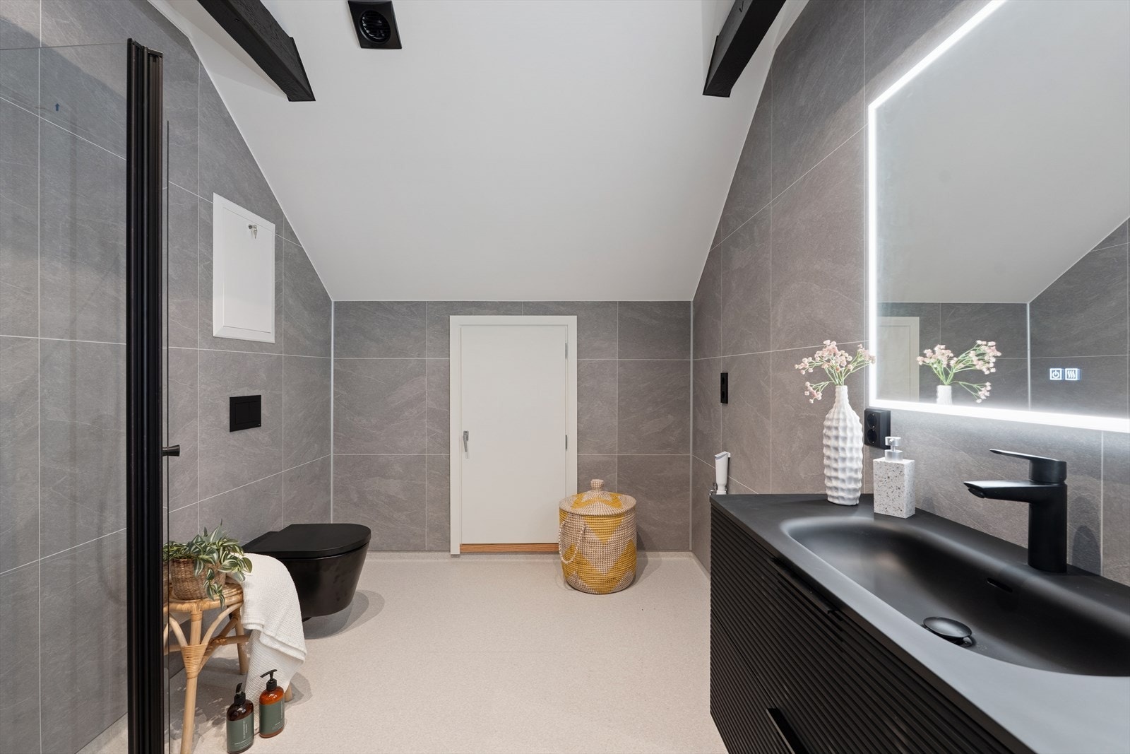 Baderommet er delikat innredet med grått vinylbelegg på gulv og grå baderomsplater på vegg som ligner fliser. I gulvet har man også varmekabler for ekstra komfort. Galleribilde