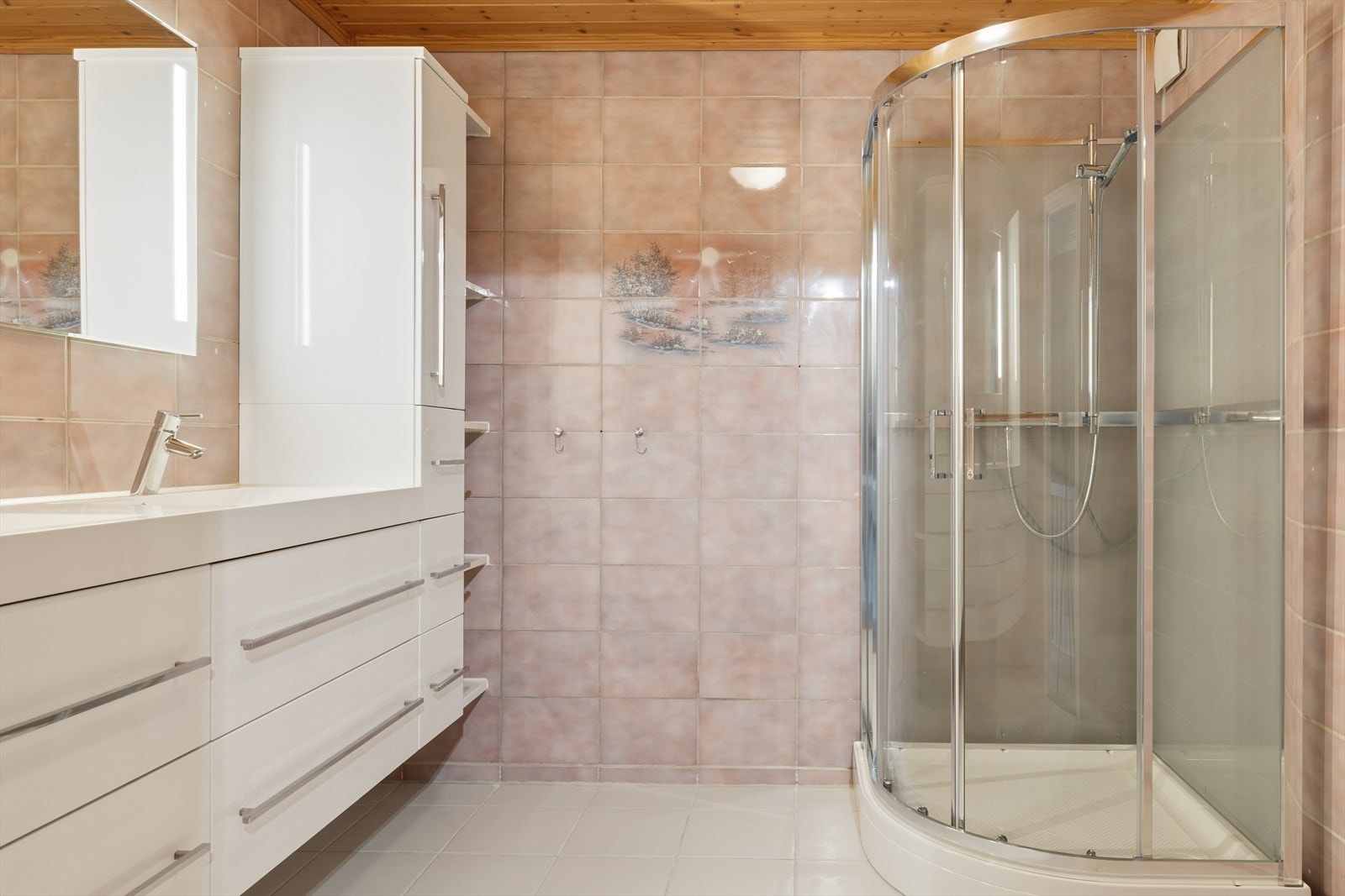 Baderommet har fliser på gulv og vegger, samt et praktisk dusjkabinett. Galleribilde