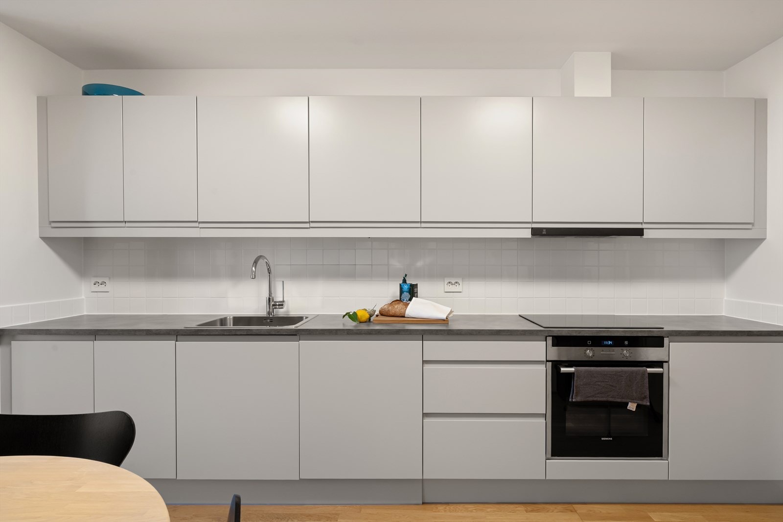 Flott kjøkken med pen kjøkkeninnredning i hvit utførelse og integrert komfyr, vifte og platetopp. Galleribilde