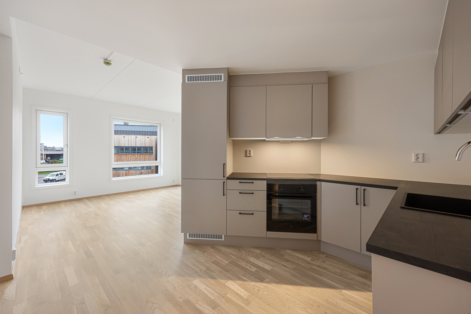 Det er glatte fronter med sorte håndtak og mørk laminat benkeplate. Galleribilde