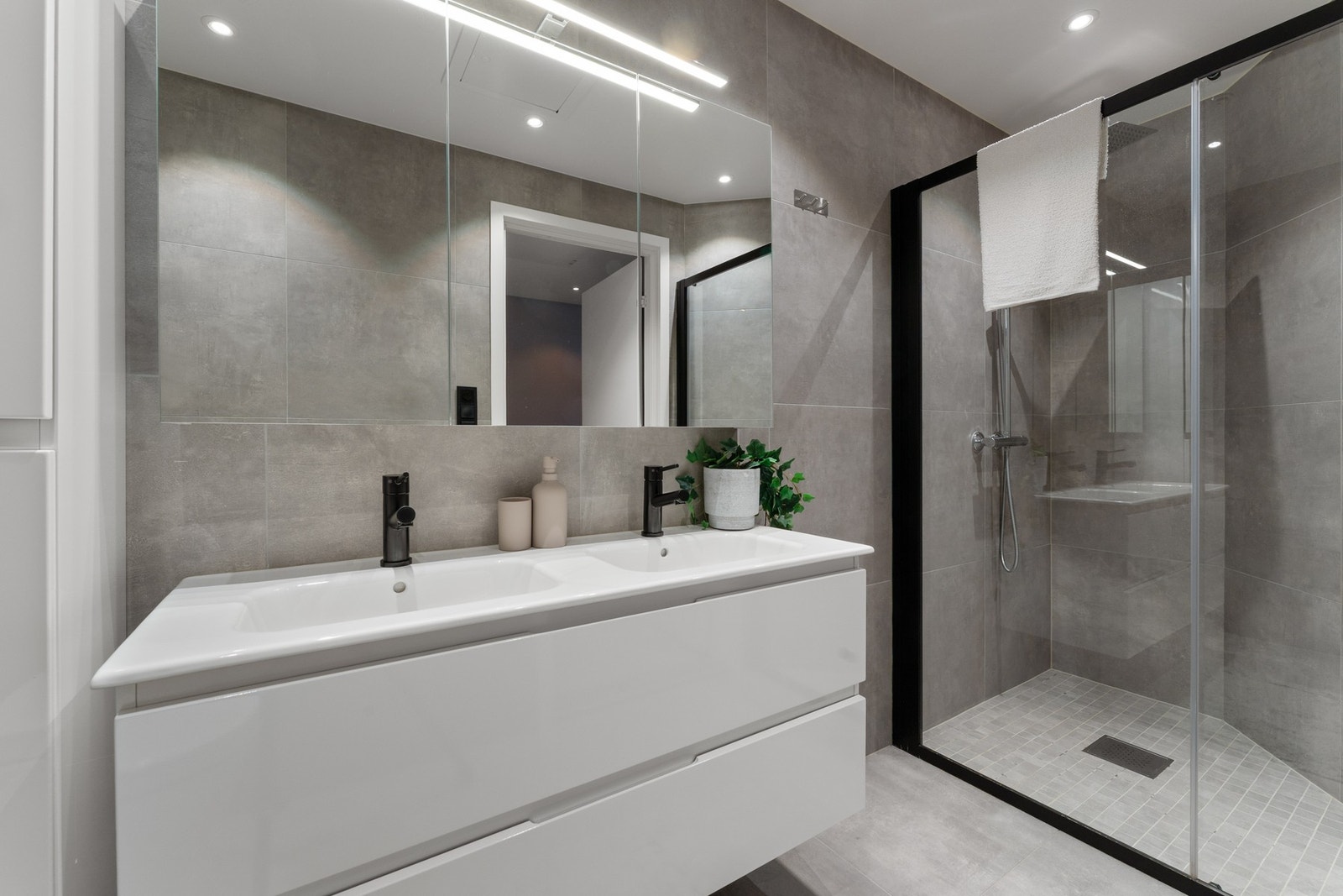 Badet i 1. etasje er utstyrt med heldekkende dobbelservant, dusj med inntreksbare skyvedører, veggehengt toalett og belyst speil. Galleribilde