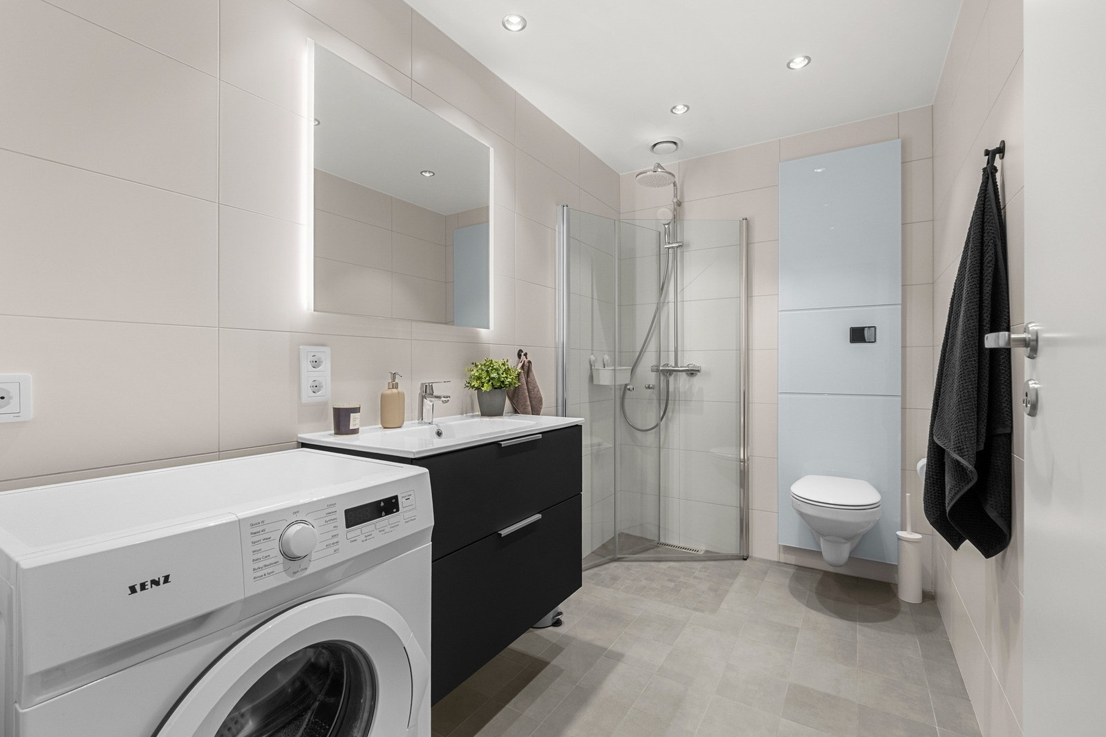 Badet har innfellbare dusjdører, vegghengt toalett, og baderomsinnredning med store skuffer. Galleribilde