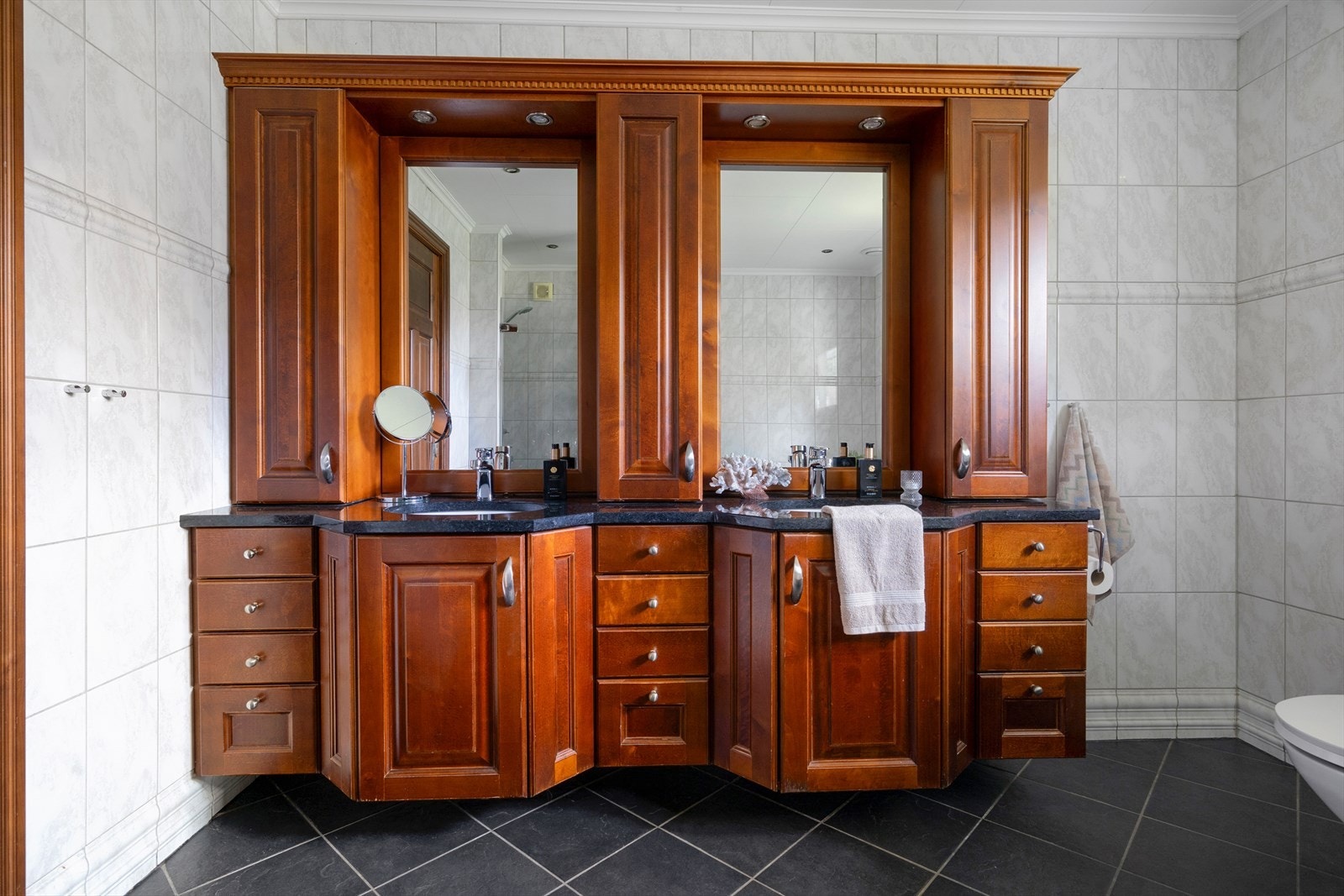 Boligens hovedbad holder en god standard og har innredning med dobbel servant, underlimt i benkeplate av stein/granitt, veggskap, speil og toalett. Et innfliset boblekar og dusjhjørne med vegg i glass og fliser gir rommet et luksuriøst preg. Galleribilde