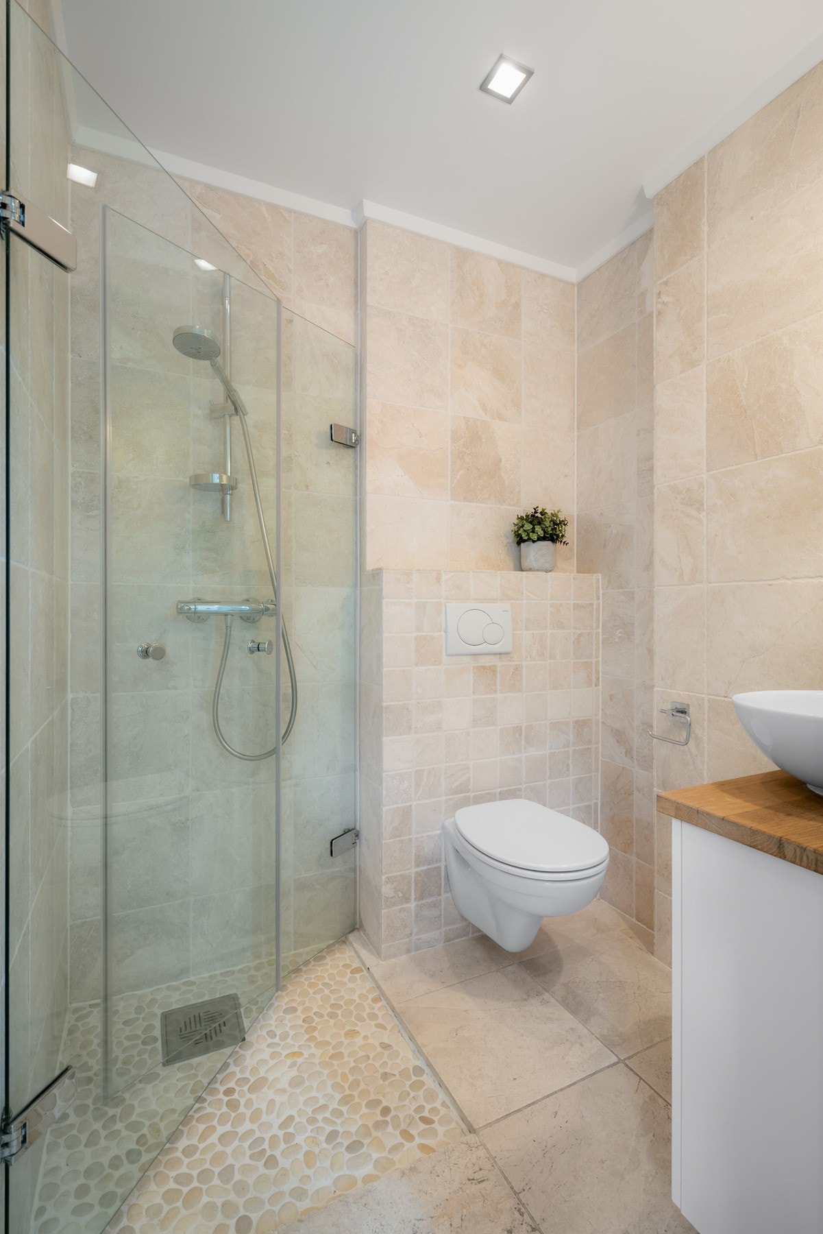 Badet i underetasjen er flislagt på gulv og vegger, og innredet med servantskap med toppmontert servant, vegghengt wc og dusjhjørne med svingdører. Galleribilde