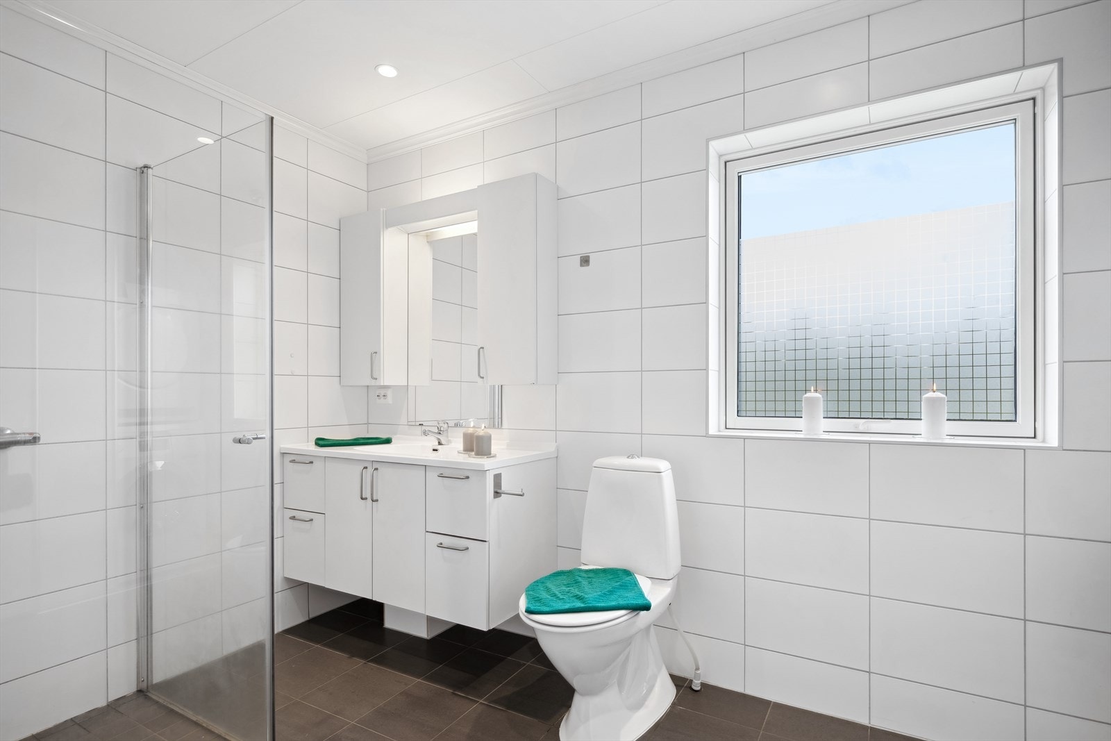 Delikat flislagt bad 1.etasje med varmekabler i gulv. Innredet med toalett, servant med skap og dusjnisje med glassdører. Galleribilde