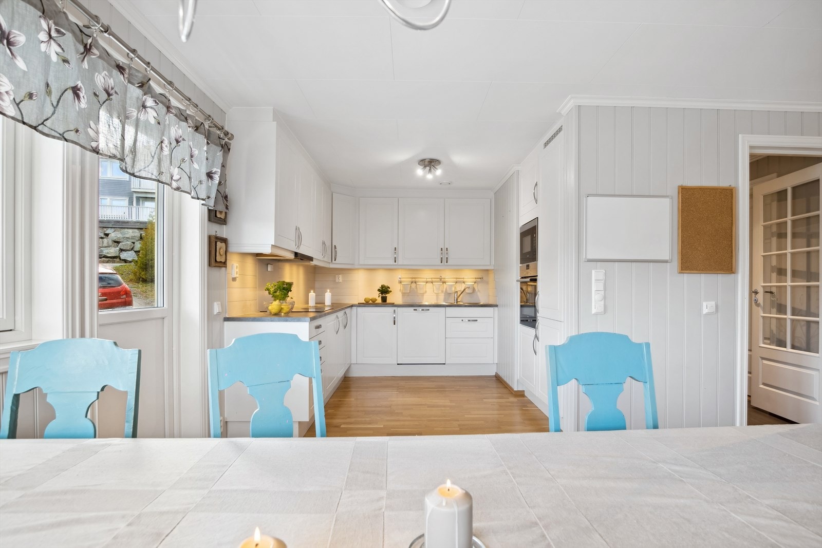 Den takhøye innredningen har klassiske hvite profilerte fronter, og en mørk laminert benkeplate. Utgang til uteplass. Galleribilde