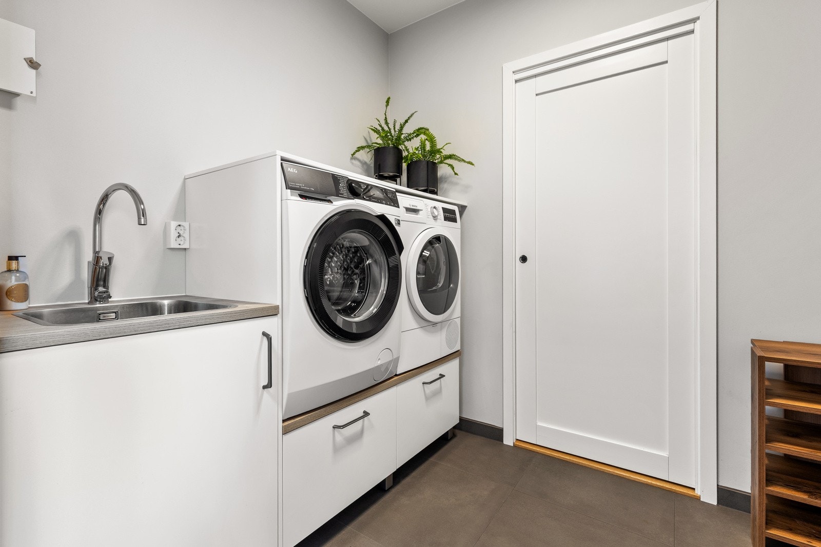 Familievennlig vaskerom i tilknytning til grov entre i 1. etasje. Inneholder bla. benkeinnredning m/skuffer, skap, utslagskum, samt opplegg for både vaskemaskin og tørketrommel. Bergvarmepumpe er plassert her. Galleribilde