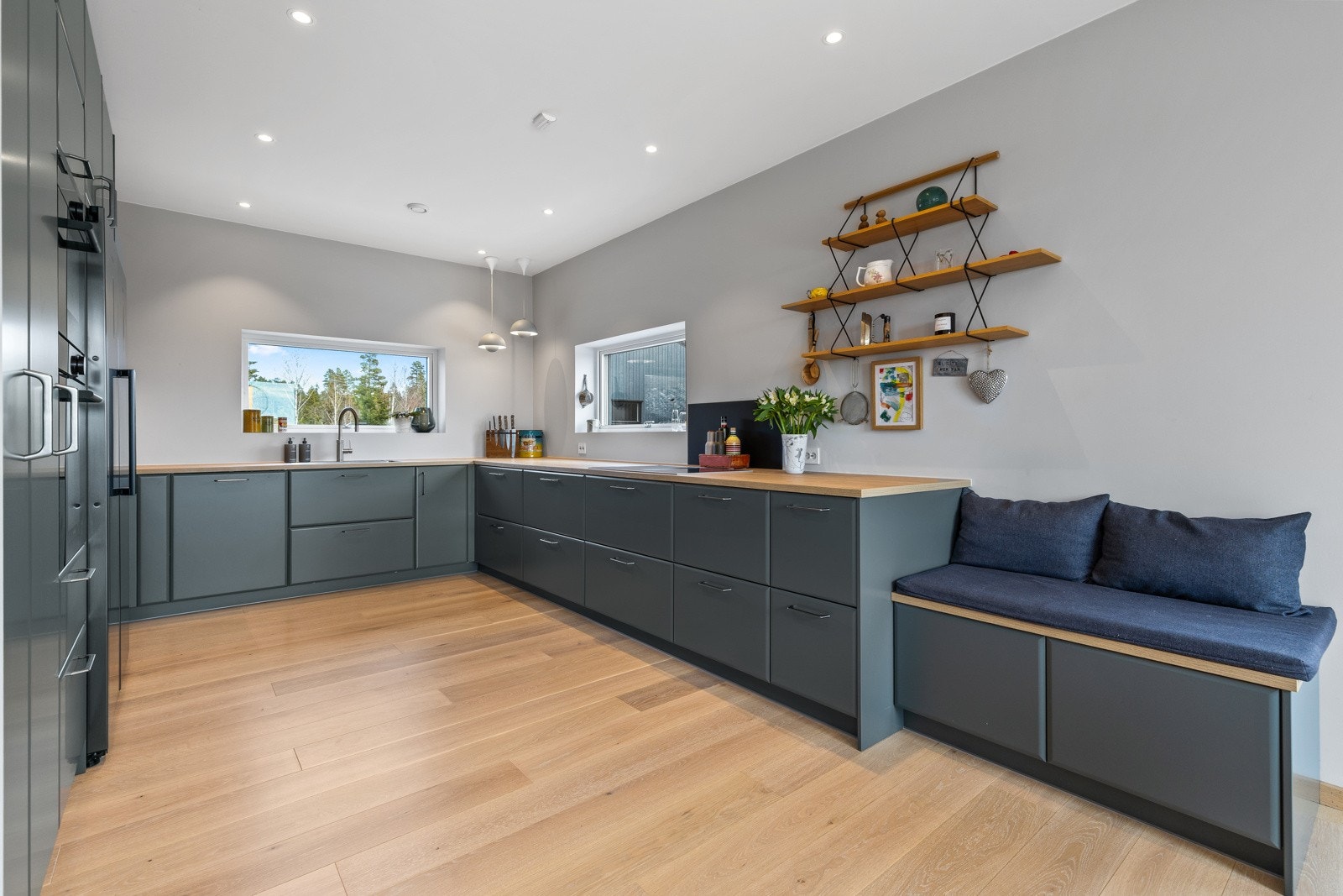 Stilrent og moderne kjøkken fra Ballingslov. Kjøkkenet er utformet i praktisk U-løsning, som gir godt med både skap- og benkeplass. De store vindusflatene slipper inn rikelig med lys og bidrar til gode arbeidsforhold ved matlagingen. Galleribilde