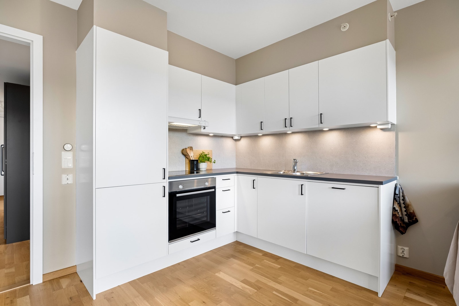 Kjøkkenet har integrerte hvitevarer som koketopp, stekeovn, oppvaskmaskin og kjøl-/fryseskap Galleribilde