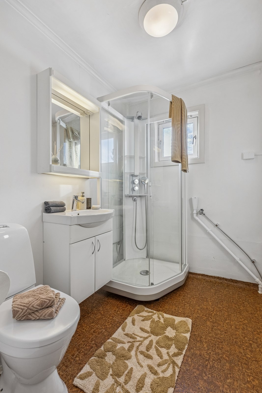 Badet har dusjkabinett, servantskap og opplegg for vaskemaskin Galleribilde