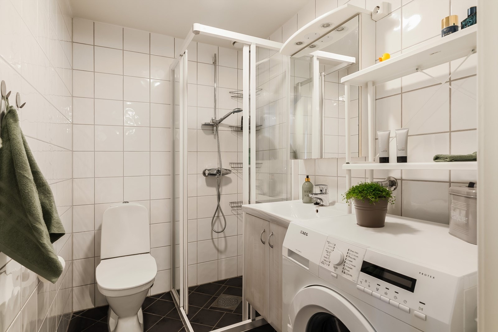 Flislagt bad med wc, servant, opplegg for vaskemaskin og dusj med skyvedør. Galleribilde