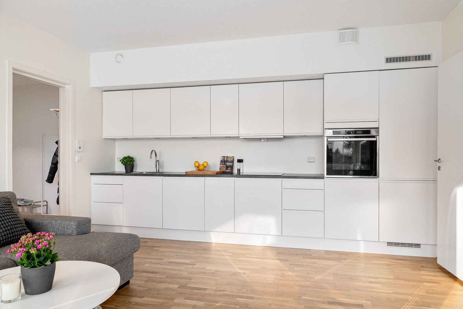 Kjøkkenet er levert av Aubo og fremstår stilrent med hvite slette fronter samt en praktisk laminatbenkeplate. Galleribilde