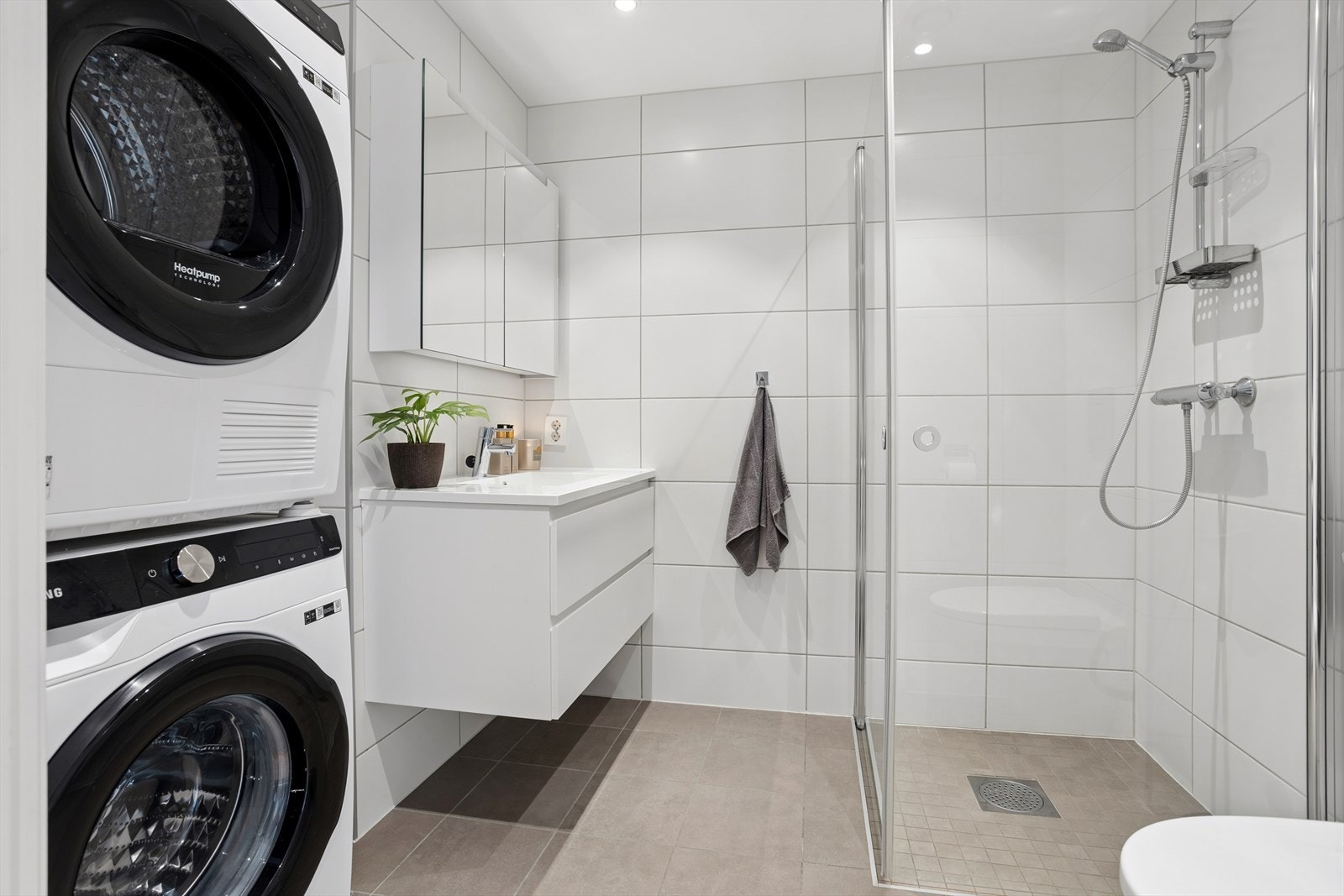 Badet er utstyrt med opplegg for vaskemaskin, servant med innredning, dusj og vegghengt toalett. Galleribilde