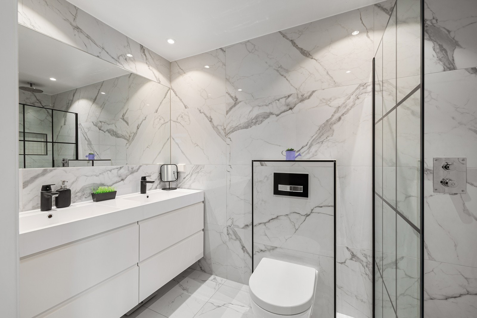 Lekkert, flislagt bad fra 2020 som umiddelbart gir et luksuriøst og moderne inntrykk. Rommet er preget av store, lyse fliser med et elegant marmormønster som strekker seg sømløst over både gulv og vegger. Galleribilde