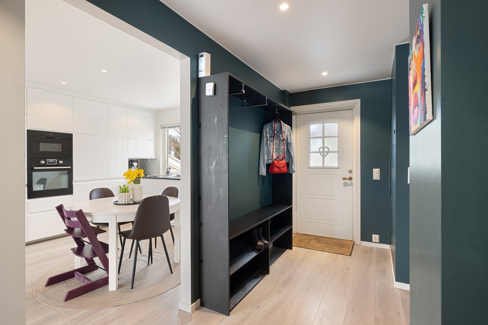 Innenfor ytterdøren blir du møtt av en innbydende entré med slette, malte veggflater og stilren laminat, som harmonerer godt med boligens øvrige rom. Galleribilde
