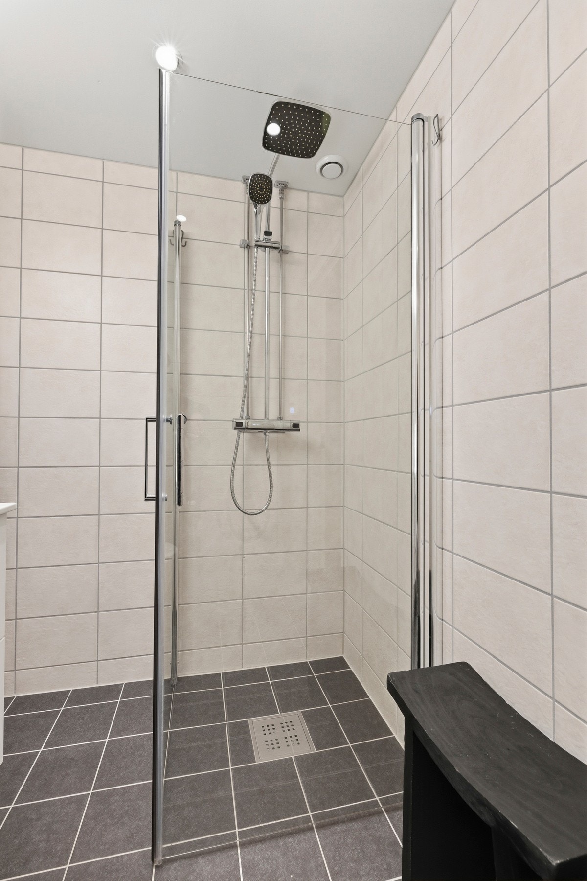 Innredningen består av servant på skap med glatte fronter, speilskap, veggfestet toalett, dusjhjørne med regnfallsdusj og opplegg for vaskemaskin Galleribilde