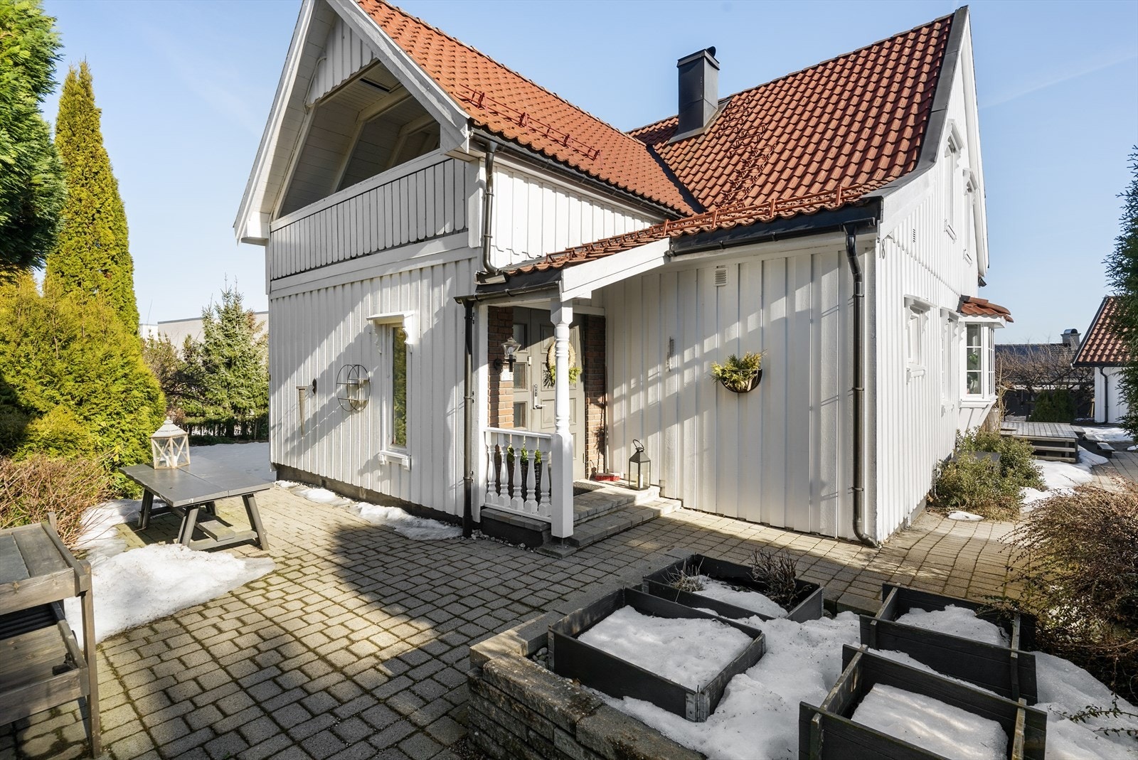 Fra gårdsplassen er det lagt belegningsstein som går videre inn mot boligens inngangsparti hvor det er et lunt og hyggelig hagemiljø. Galleribilde