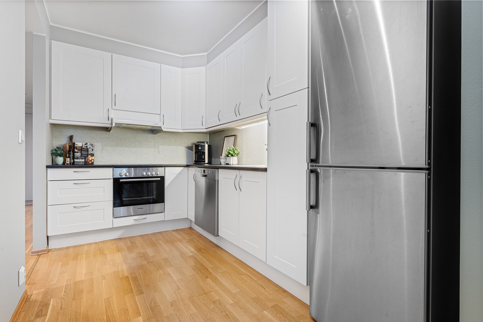 Det er god skap- og benkeplass, samt hvitevarer som komfyr, oppvaskmaskin og kjøl/frys. Et lyst og tidløst kjøkken som passer godt inn i boligens stil Galleribilde