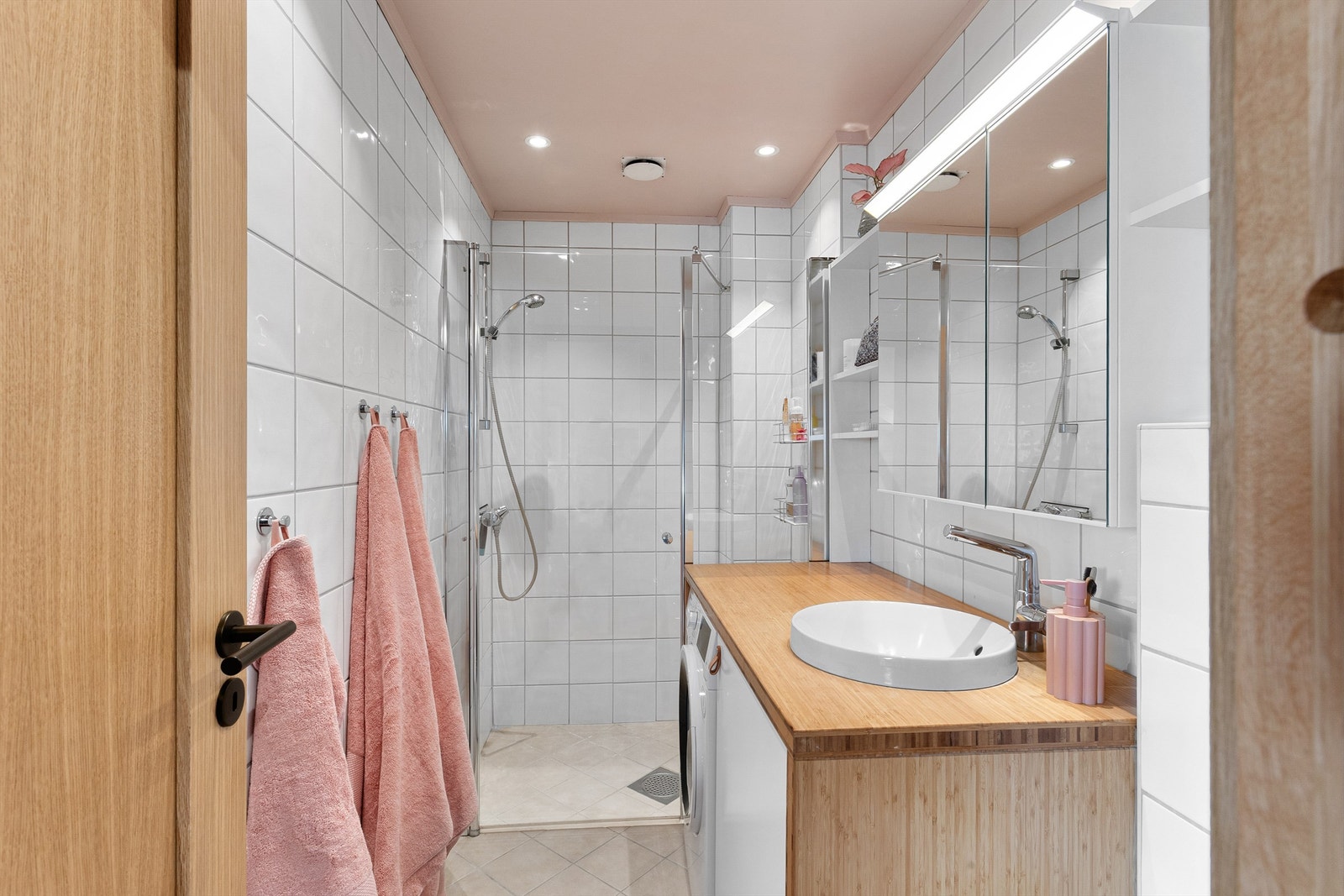 Badet har en moderne innredning med himling av malte plater, innfelte downlights og fliser med elektrisk gulvvarme Galleribilde