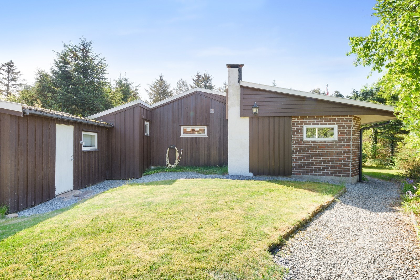 Bygningen har stående trepanel og teglsteinsmur. Galleribilde