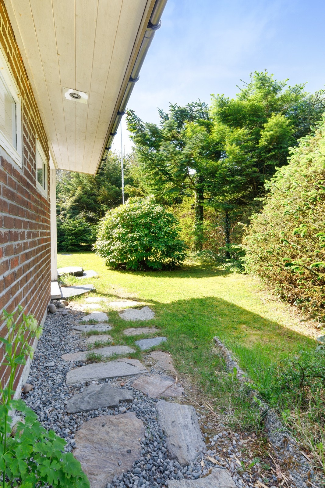 Steinlagt gangsti ved siden av boligen leder til hovedinngang, terrasse og hage. Galleribilde