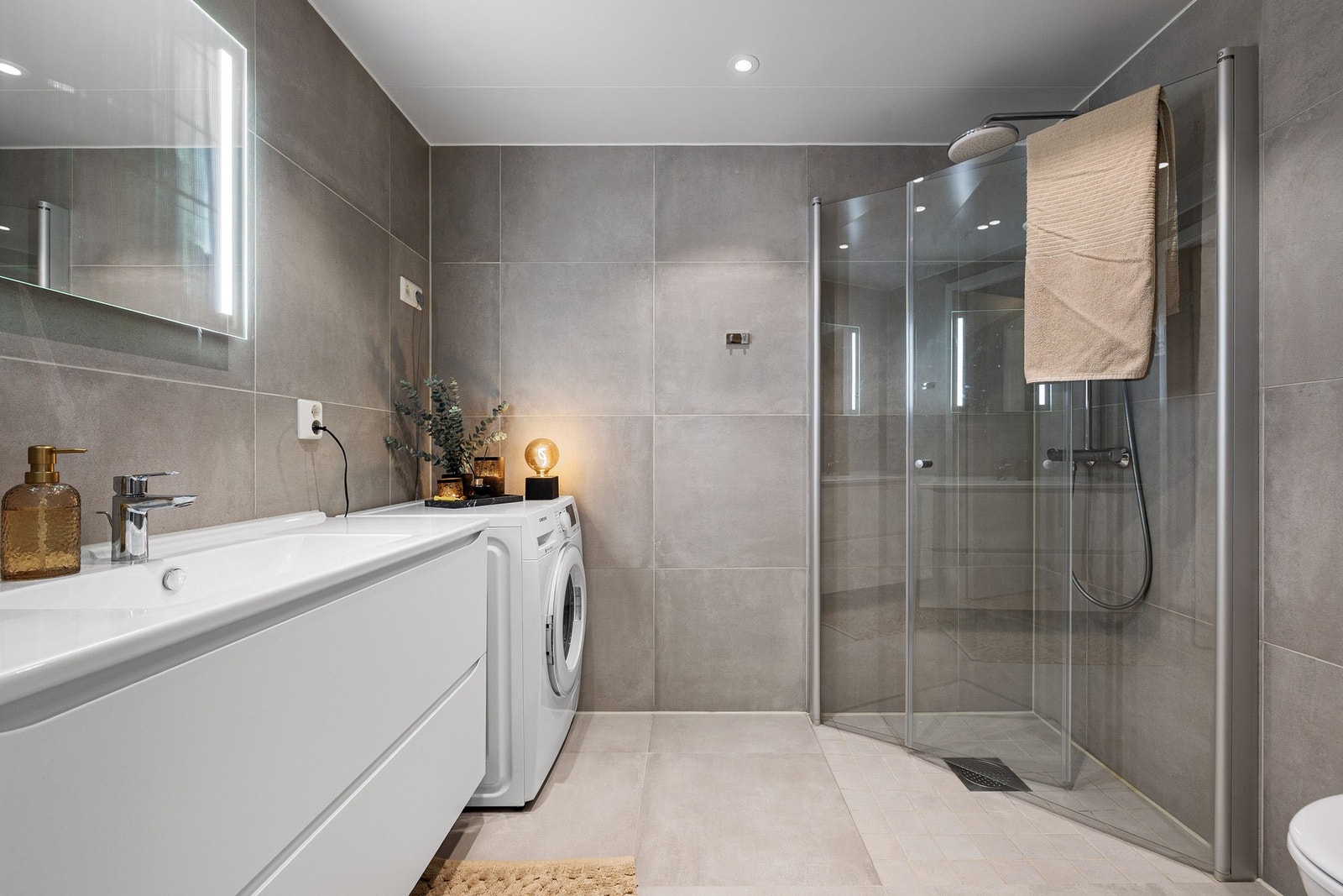 Leilighetens bad fremstår velholdt og moderne med fliser på både gulv (vannbåren gulvvarme) og vegger. Den gode standarden bekreftes av takstmann med tildelt tilstandsgrad 0. Galleribilde