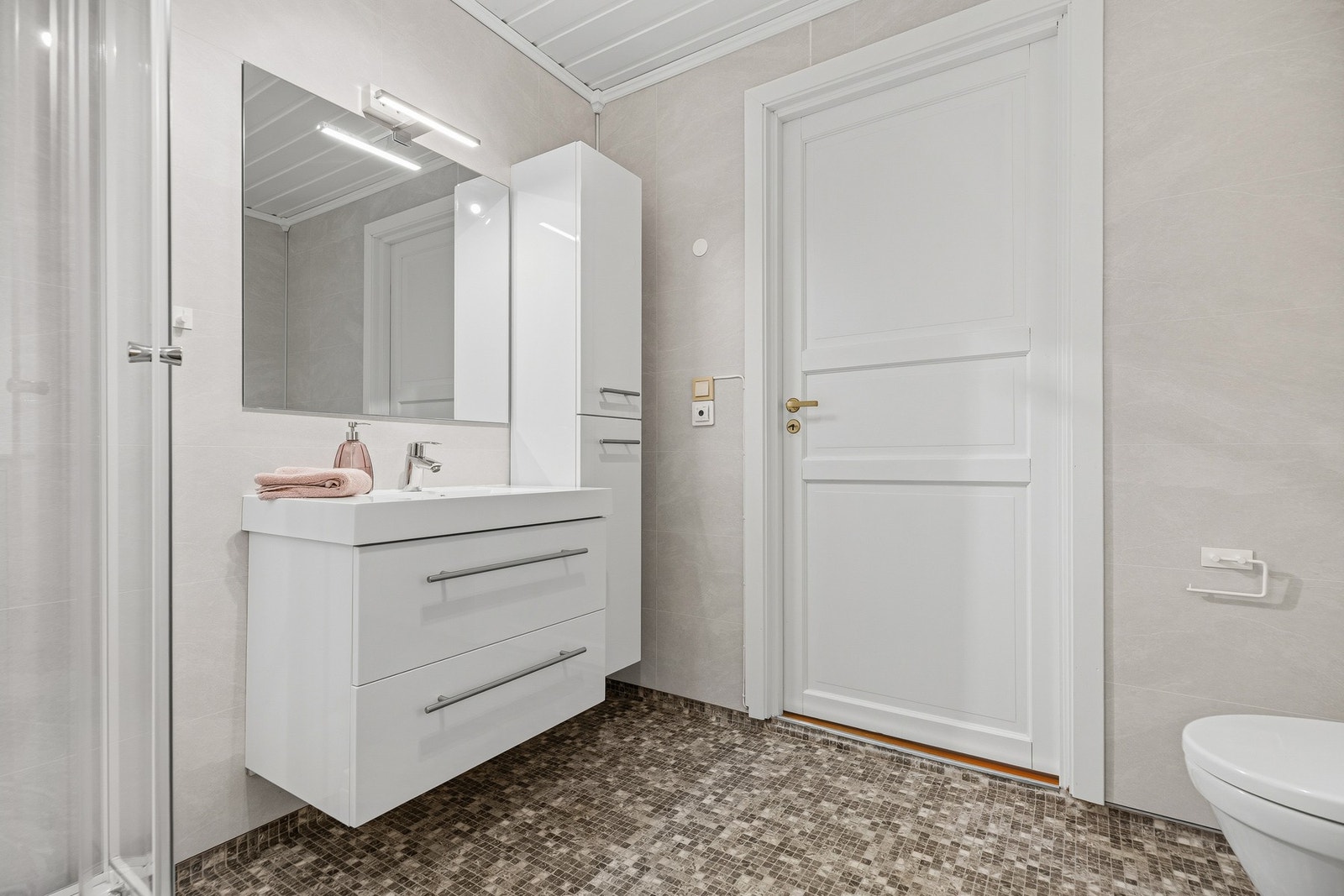 God oppbevaringsplass med veggmontert høyskap i tillegg til skuffer i servant. Det er varmekabler i gulvet Galleribilde